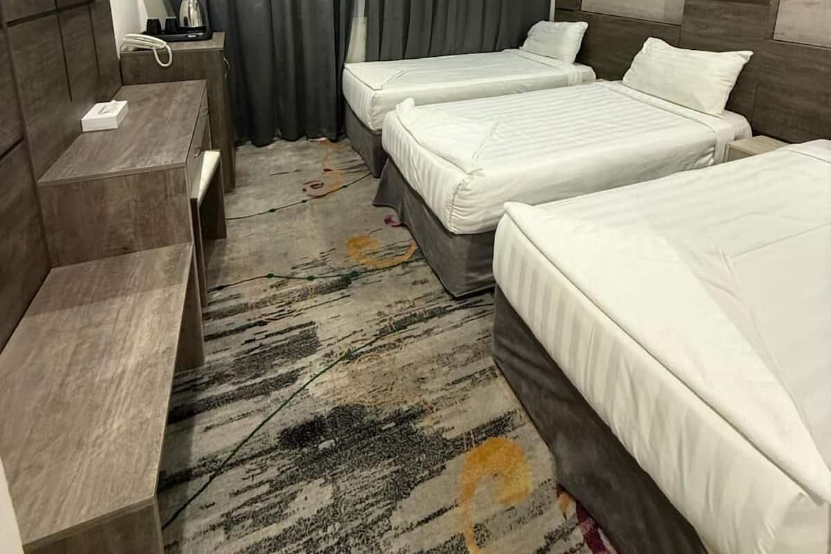 Habitación de hotel con dos camas, un escritorio, un televisor de pantalla plana y un amplio ventanal con cortinas.