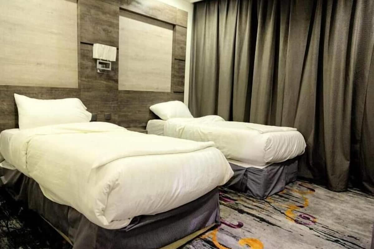 Una habitación de hotel con dos camas, un ventanal grande y una cortina.
