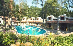 Ein Pool, umgeben von Bäumen und einem Gebäude mit mehreren Balkonen.