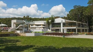 A modern building with a staircase leading to an upper level, surrounded by a grassy area and trees. - VILLAS ROPOTAMO (Kiten)