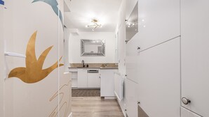 Een moderne keuken met witte kasten, een centraal eiland en een decoratieve spiegel.