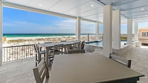 A covered outdoor area with a pool, tables, and chairs, overlooking a beach and ocean. - Newly built | Luxury Gulf-front Home | Private Pool | Elevator | Game Room (Pensacola Beach)