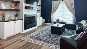 Ein Wohnzimmer mit Kamin, Flachbildfernseher, Sofa und Couchtisch.