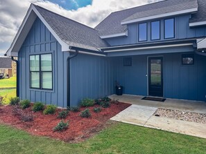 A modern two-story house with a dark blue exterior, a sloped roof, and a front porch.