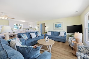 Ein Wohnzimmer mit blauen Sofas, einem runden Couchtisch und einem Flachbildfernseher.