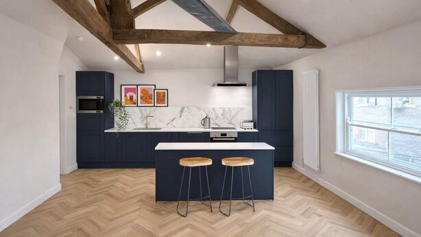 A modern kitchen with dark cabinets, a marble countertop, wooden beams, and a large window. - The Bridge - Penthouse Apartment (York)