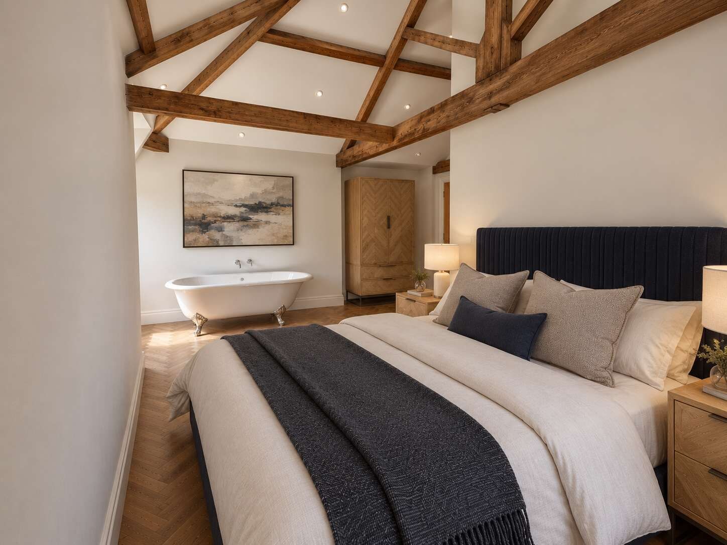 Een slaapkamer met een groot bed, een nachtkastje, een lamp, een houten garderobe en een vrijstaand bad.