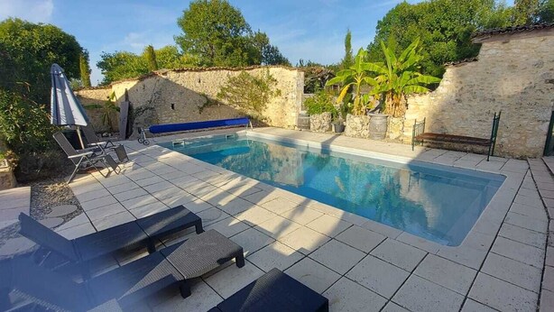 Una piscina amb gandules i una paret de pedra.