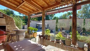 Terrassa exterior amb mur de pedra, mobiliari de fusta i plantes en testos.