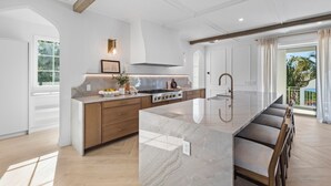 Een moderne keuken met een marmeren eiland, houten kasten en een groot raam.