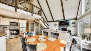 Una cocina amplia con electrodomésticos modernos, un comedor con mesa de madera, y una escalera que lleva a un nivel superior.