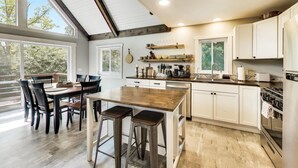 Una cocina moderna con una isla de madera, taburetes de bar y electrodomésticos integrados.