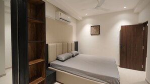 Ein modernes Schlafzimmer mit Bett, eingebauten Regalen, einer Klimaanlage, einem Deckenventilator und einem Holzschrank.