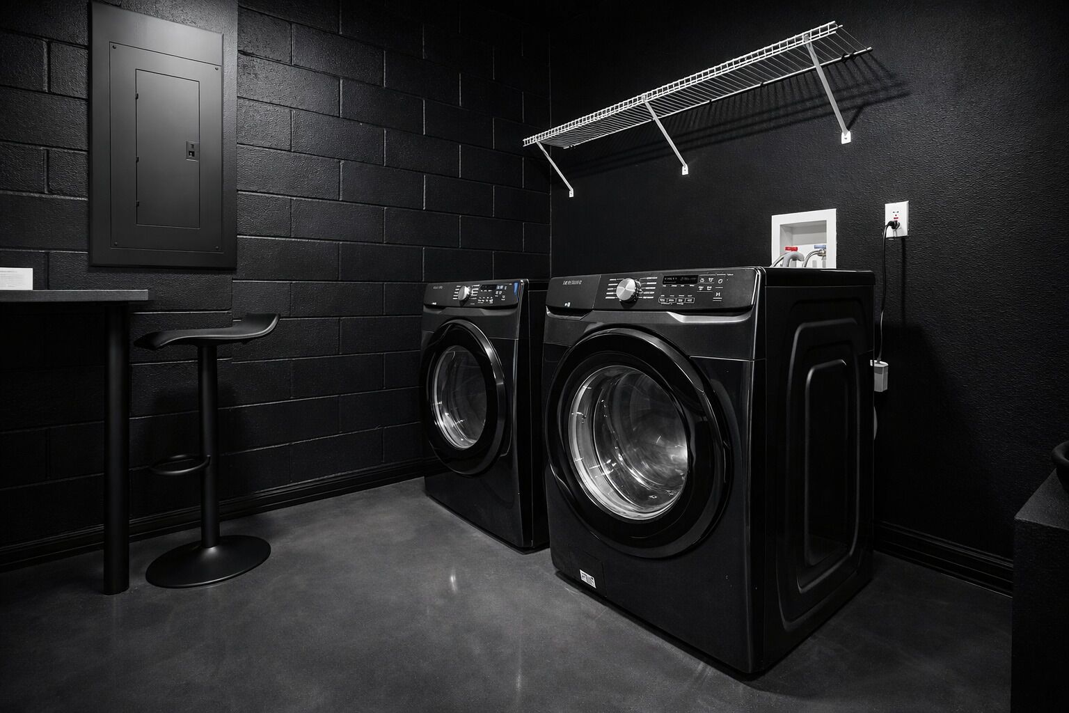 A laundry room with two front-loading washing machines, a metal drying rack, a wall-mounted electrical panel, and a small stool.