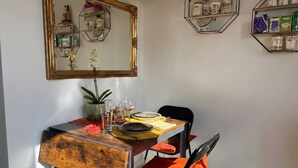 Una zona de menjador amb taula de fusta, cadires i un mirall a la paret.