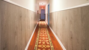 A hallway with wooden paneling, a red carpet, and an exit sign. - 0ne bed with shared   bathroom (Toronto)