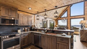 A spacious kitchen with wooden cabinets, stainless steel appliances, and a large island. - Epic Mountain Views: Hot Tub, Games and Firepit (Ellijay)