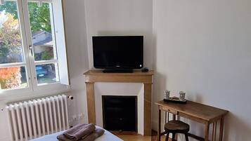 Een slaapkamer met een groot bed, een televisie op een standaard, een houten bureau en een hanglamp.