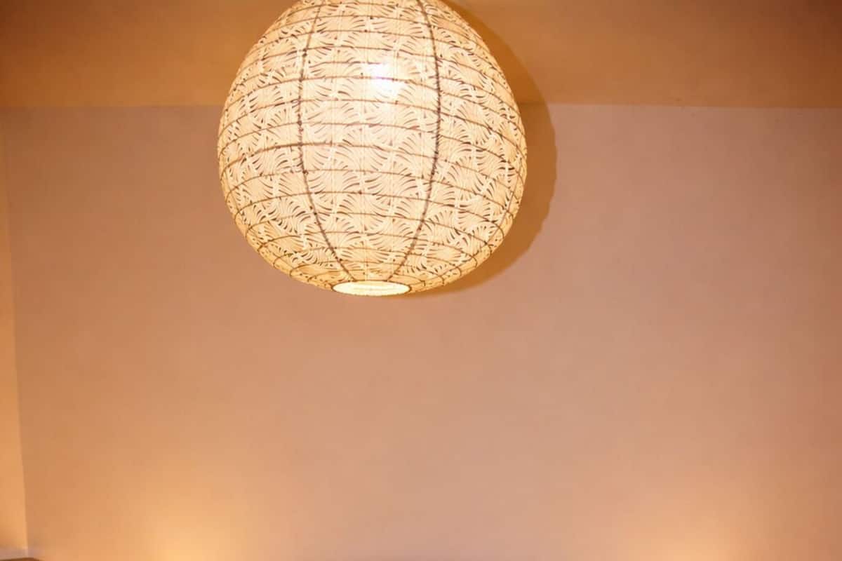 Un lit avec une couvre-lit blanche et jaune, une tête de lit sombre et deux lampes de chevet.