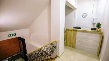 A staircase with an exit sign, a reception desk, and a clock on the wall.