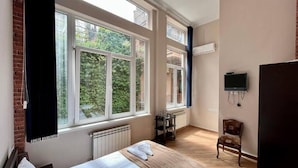 A bedroom with a large bed, two windows, a radiator, a TV, and a chair. - Tamarisi Old Tbilisi (Tbilisi)