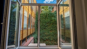 A view through a window of a building with wooden siding and a green ivy-covered wall. - Tamarisi Old Tbilisi (Tbilisi)