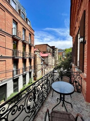 A balcony with a wrought iron railing, a round table, and a wicker chair. - Tamarisi Old Tbilisi (Tbilisi)