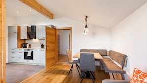 A modern kitchen with white cabinets, a built-in oven, and a wooden ceiling.