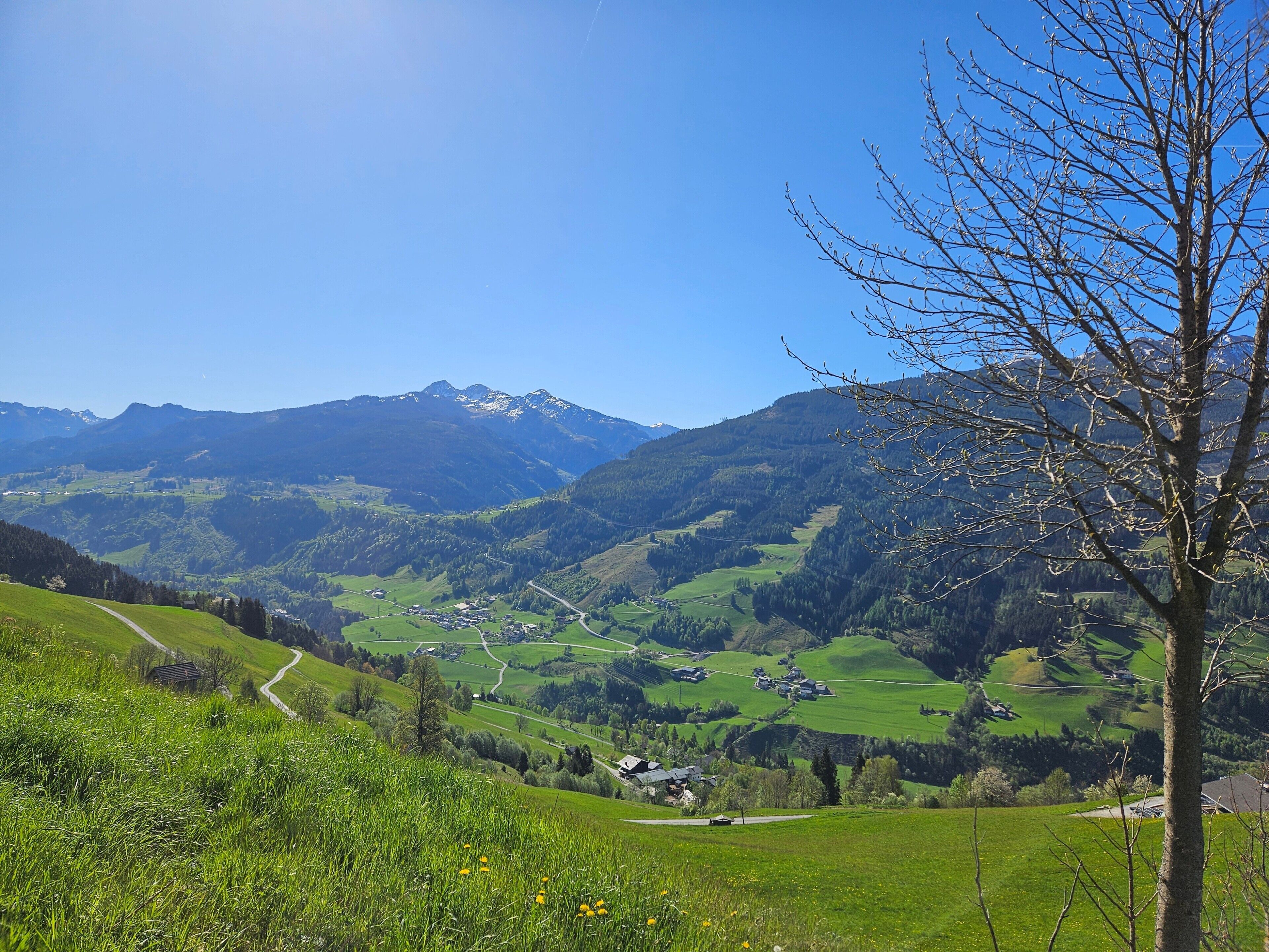 Eine gebirgige Landschaft mit blauem Himmel, einer kurvenreichen Straße und einer kleinen Siedlung.