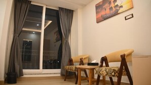 Una habitación con un amplio ventanal corredera, un sofá, una mesita y un cuadro en la pared.