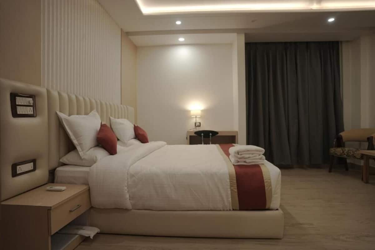 Une chambre d’hôtel avec un grand lit, une table de chevet, une lampe et une chaise.