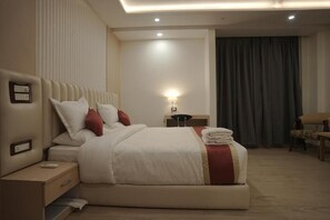 Ein Hotelzimmer mit einem großen Bett, einem Nachttisch, einer Lampe und einem Sessel.