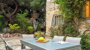 An outdoor patio with a glass-top table, four chairs, and a fruit bowl. - Historic & Modern Home with Garden (Haifa)
