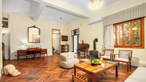 A spacious living room with a wooden herringbone floor, a dining table with chairs, a sofa, and a fireplace. - Historic & Modern Home with Garden (Haifa)