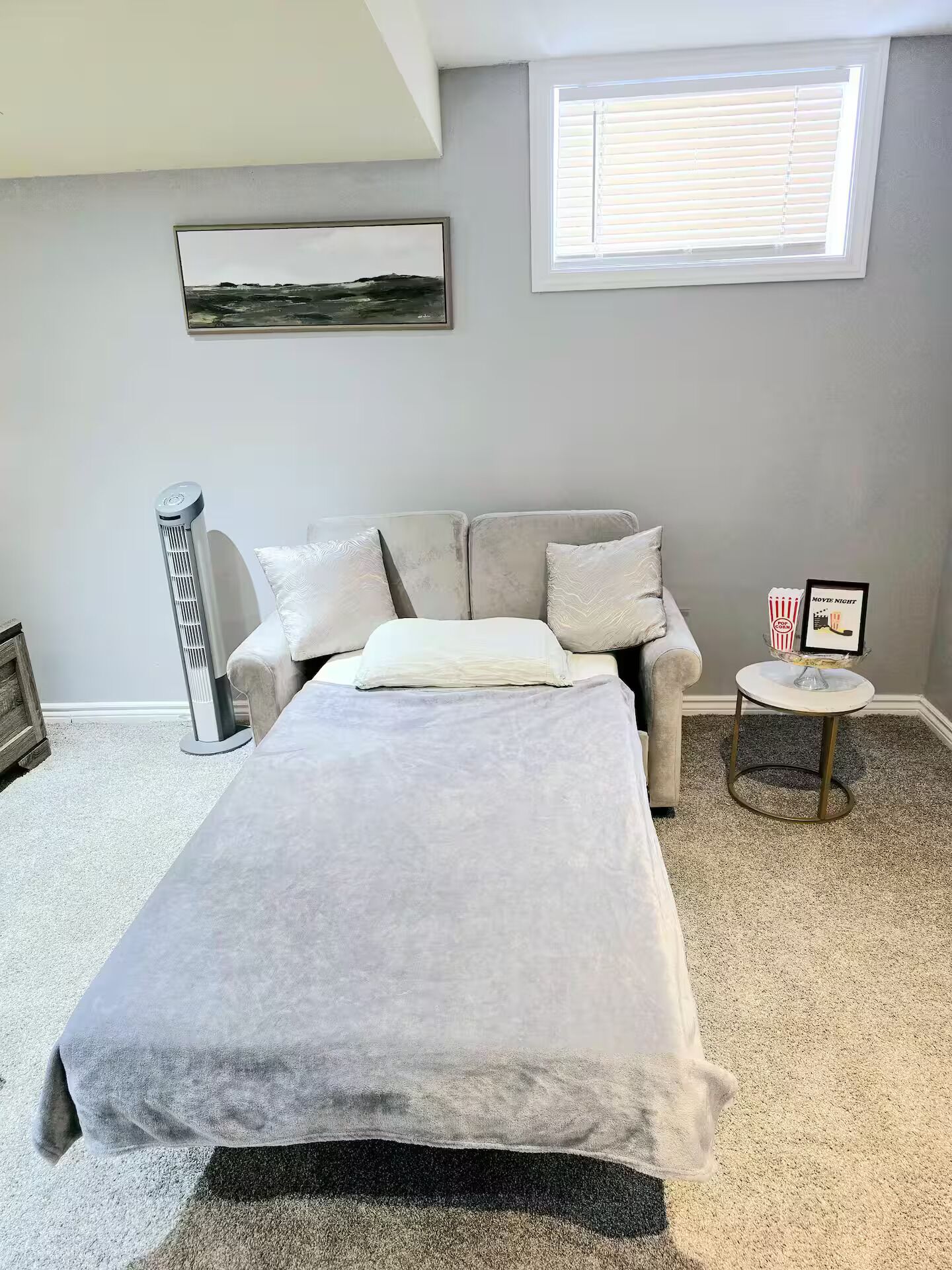 Une chambre à coucher avec un lit, un radiateur, une fenêtre et un tableau encadré accroché au mur.