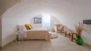 A cozy bedroom with a bed, bedside table, and a small table with chairs. - Masseria Mammella with pool and by the beaches (Puglia)