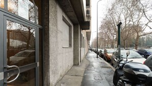 Ein Gebäude mit Glastür, heruntergelassener Rolltür und einer Reihe geparkter Rollermopeds.