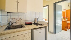 Eine kleine Küche mit Spüle, einer Kaffeemaschine und einem kleinen Kühlschrank.
