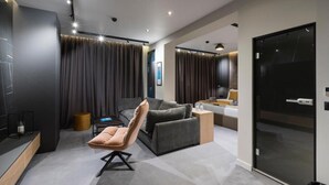Una sala moderna con un sofá gris, un sillón con reposabrazos y una mesita de madera.