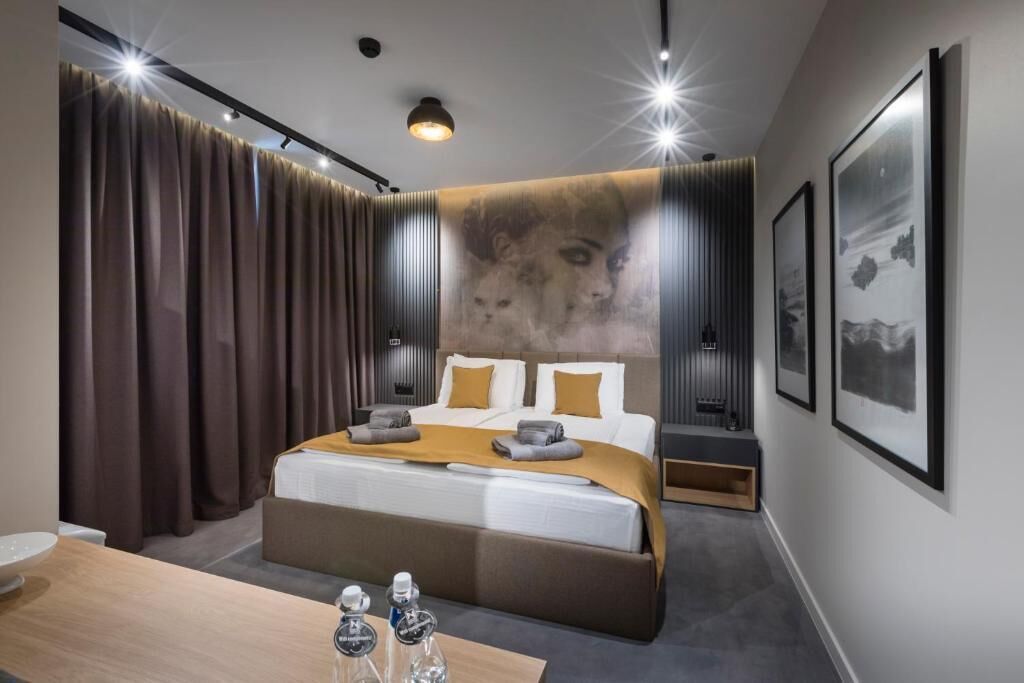 A modern hotel room with a large bed, a wooden desk, and a wall-mounted TV.