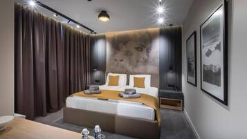 A modern hotel room with a large bed, a wooden desk, and a wall-mounted TV.