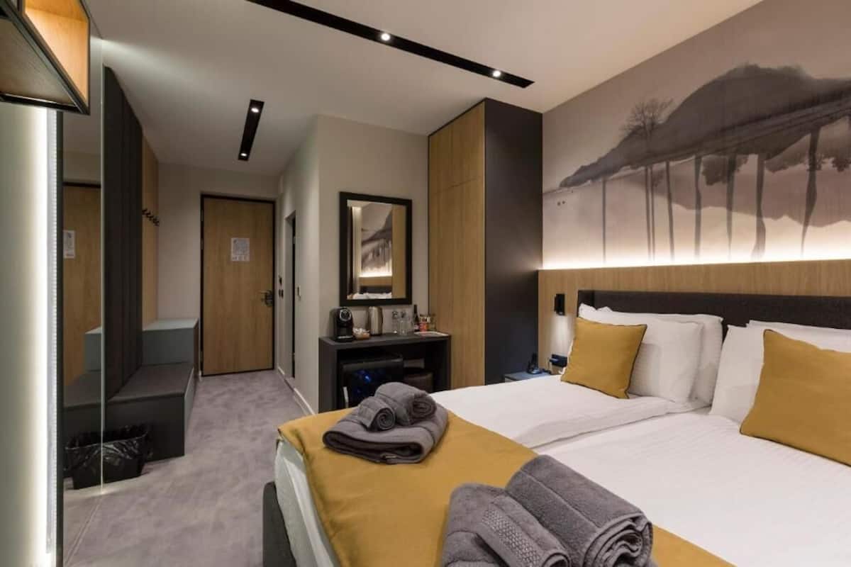 A modern hotel room with a large bed, a desk, and a mirror.