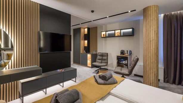 Una habitación de hotel moderna con televisión de pantalla plana, sofá, cama, escritorio y una silla.