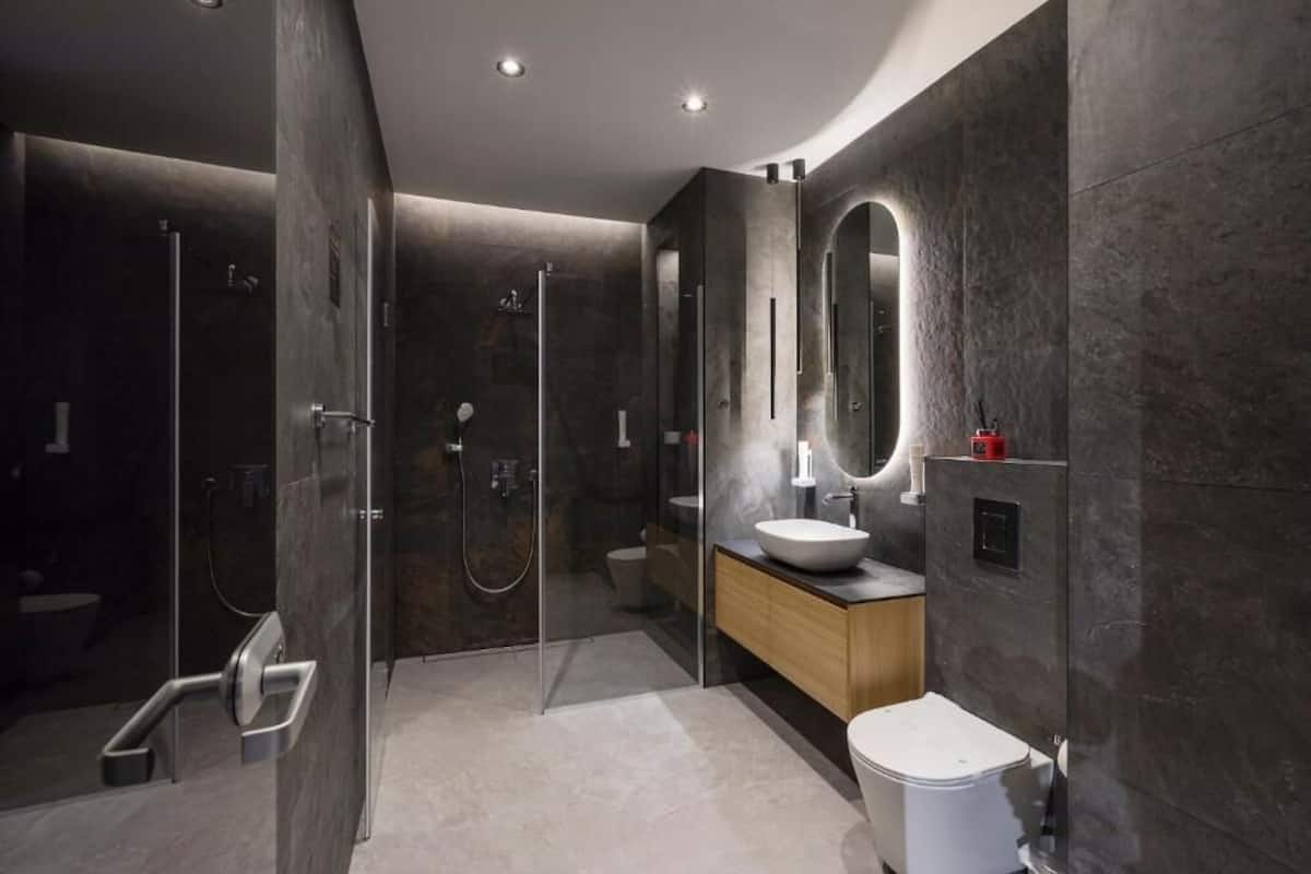 A modern bathroom with a glass-enclosed shower, a wooden vanity, and a large mirror.