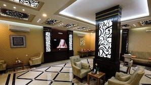 A lobby with a checkered floor, seating area, decorative panels, and a television screen. - ALFASWAL ALARBAAH SERVICED APARTMENT  (Taif)