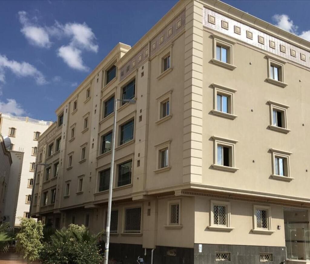 A multi-story building with a beige facade, multiple windows, and a flat roof.