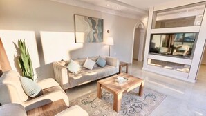 A modern living room with a sofa, coffee table, and decorative rug. - ALFASWAL ALARBAAH SERVICED APARTMENT  (Taif)