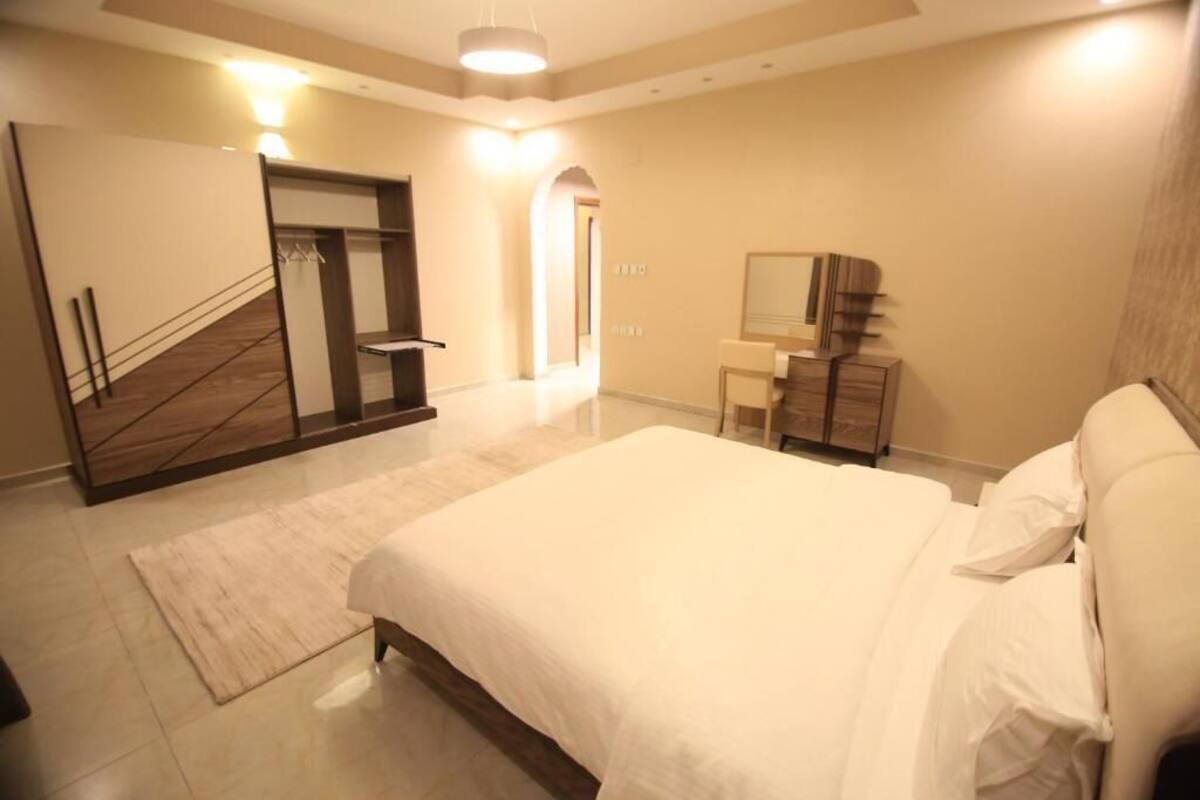 Un dormitorio con una cama grande, un armario, un espejo y una escalera.