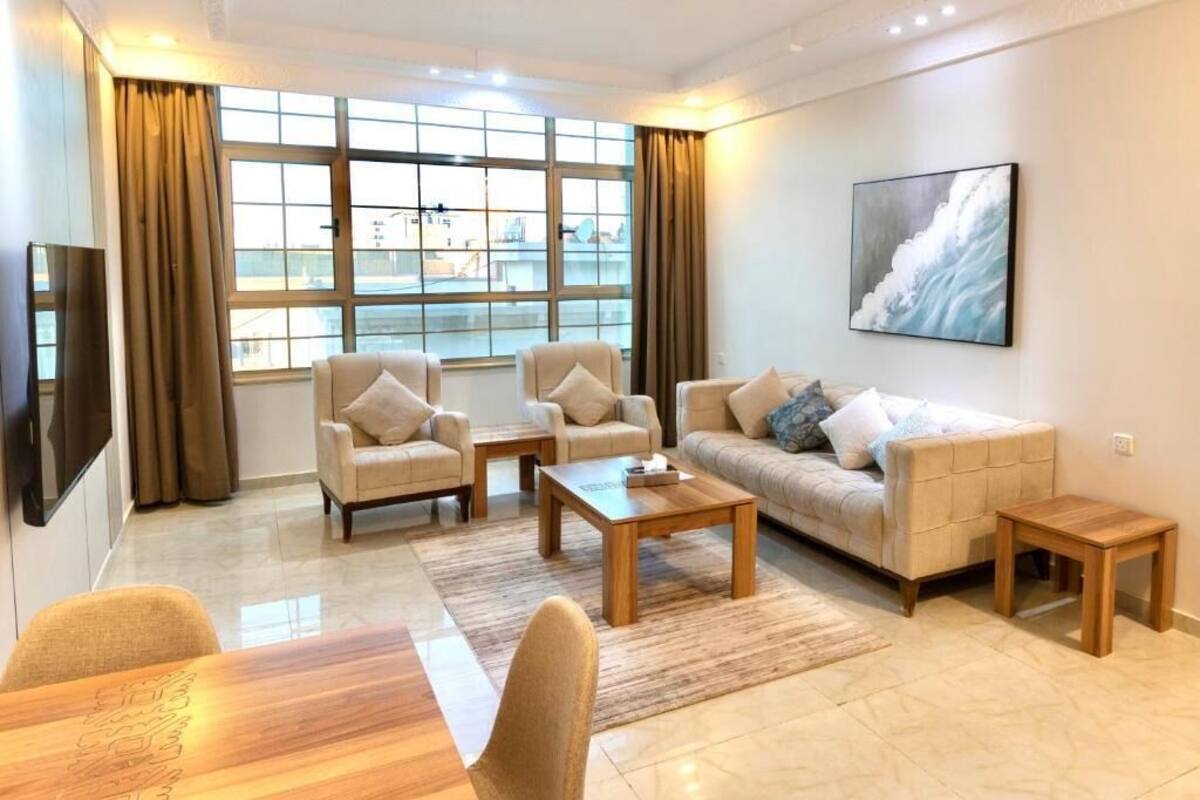 Una sala de estar moderna con un sofá, sillones, una mesa de centro y un televisor.