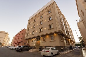 A multi-story hotel with a prominent entrance, a parking lot, and a clear sky. - ALFASWAL ALARBAAH SERVICED APARTMENT  (Taif)